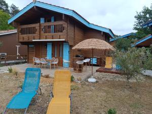 a house with a deck with chairs and an umbrella at Loue chalet in Bias