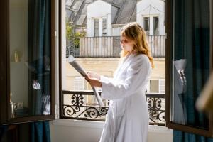 a woman standing on a balcony looking out a window at Hotel Etoile Saint Ferdinand by Happyculture in Paris