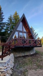 a small cabin with a triangular roof and glass windows at A-Frame Tadić Tara in Ljuboš