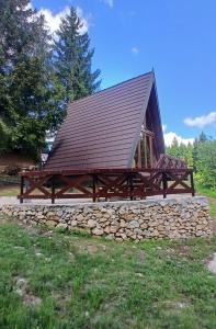 a large wooden pavilion with a stone wall at A-Frame Tadić Tara in Ljuboš