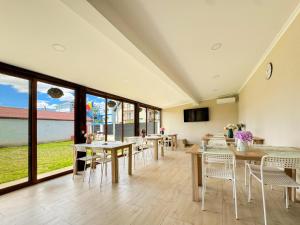 a dining room with tables and chairs and windows at Pensiunea Riviera in Costinesti