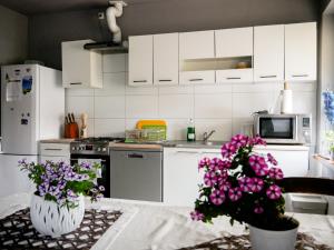a kitchen with white cabinets and purple flowers on a table at Dom jednorodzinny NOWA in Dęblin