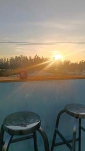 two stools sitting on top of a pool with the sunset at Perla Home in Danang