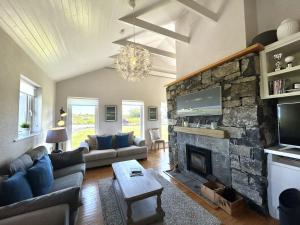 a living room with a couch and a stone fireplace at Murlach Moorings in Ballyconneely