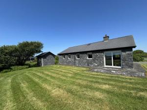 a stone house with a large lawn in front of it at Murlach Moorings in Ballyconneely