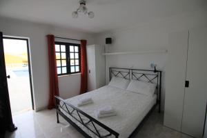 a bedroom with a bed with white sheets and a window at Charming Vila Van Gogh in Luz +9 photos