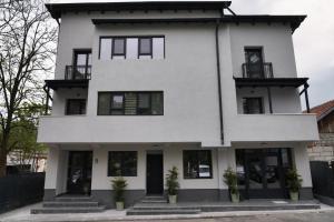a white house with black windows at Skylark Apartments in Râmnicu Vâlcea