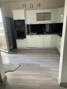 a kitchen with white cabinets and black appliances at Slnečný byt pri lesoparku in Prievidza