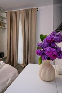 a vase of purple flowers on a table in a bedroom at Skylark Apartments in Râmnicu Vâlcea