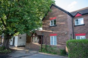 a brick house with red windows and a tree at Saram Lodge Lichfield in Lichfield