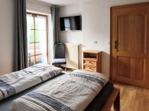 two beds in a room with a door and a chair at Ferienwohnung Soiernblick Krün Bärnbichl in Krün