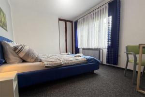 a bedroom with a blue bed and a window at ASGARD Guesthouse in Josipdol