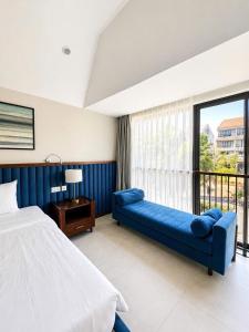 a bedroom with a blue couch and a large window at AnHuy Villa in Phú Quốc