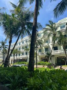 a large white building with palm trees in front of it at AnHuy Villa in Phú Quốc