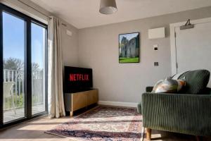 a living room with a tv and a chair and a window at Hawthorn Stays in Maynooth +4 photos