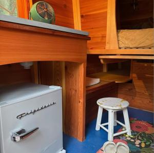 Ein kleiner weißer Kühlschrank in einem holzgetäfelten Raum mit einem Hocker. in der Unterkunft Bitty Bunky in Nelson + 11 Fotos