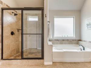 a bathroom with a tub and a shower with a window at Unpack and Unwind in Yukon +16 photos