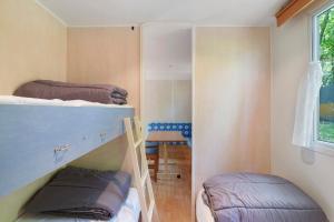 two bunk beds in a small room with a window at 22.Mobil-home option clim 5pers in Calviac