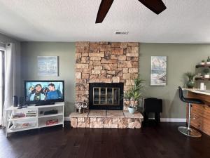 a living room with a tv and a stone fireplace at Baypoint Condo, Pool, Dock, relaxing location in Lake Ozark