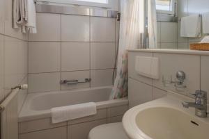 a bathroom with a sink and a toilet and a tub at Amanthos Living Zürich Airport in Glattbrugg +19 photos