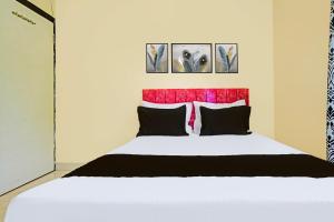 a bedroom with a white bed with a red headboard at Hotel O Paradise Green in Indore