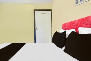 a bedroom with a bed with black pillows and a door at Hotel O Paradise Green in Indore