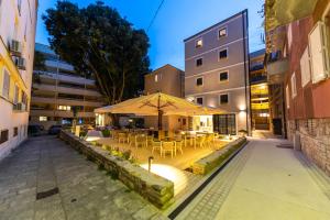 a patio with tables and chairs and an umbrella at Hidden Tree Heritage Hotel in Zadar