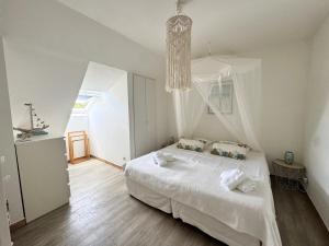 a bedroom with a white bed and a chandelier at Horizon Doré Appt avec piscine - vue sur mer in Gourbeyre +37 photos
