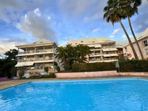 a resort with a swimming pool in front of a building at Horizon Doré Appt avec piscine - vue sur mer in Gourbeyre