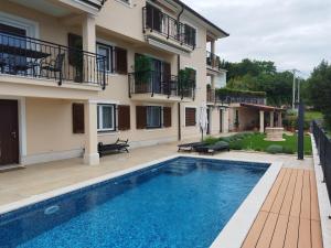 a villa with a swimming pool in front of a house at Apartments Villa Elma in Mošćenička Draga