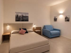 a bedroom with a bed and a blue chair at B&B LE MAGNOLIE in Termoli