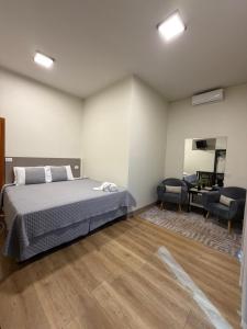 a bedroom with a bed and two chairs and a desk at Him Hotel in Iraí de Minas