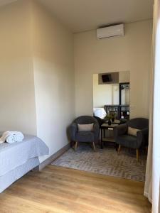 a bedroom with a bed and two chairs and a desk at Him Hotel in Iraí de Minas