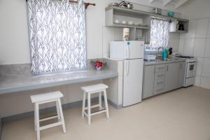 a kitchen with a white refrigerator and two stools at Neem View Apartments - Studio in Falmouth