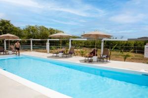 a swimming pool with chairs and umbrellas and a person at Neem View Apartments - Studio in Falmouth