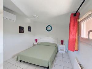 a white bedroom with a bed and a window at Cottage clim piscine in Saint-Saturnin-lès-Avignon