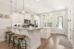 a kitchen with white cabinets and bar stools at Garden Cottage 89 in Jekyll Island
