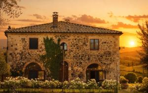 an old stone house with a sunset in the background at Il Cerchio delle Streghe Country House al Podere Casella in Castiglione dʼOrcia