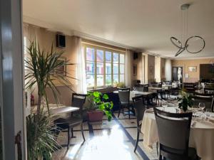 a dining room with tables and chairs and plants at Logis Hôtel du Pont Neuf in Le Veurdre