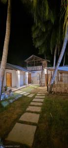 a house at night with palm trees and a walkway at Holabay Surf Hostel in Arugam Bay