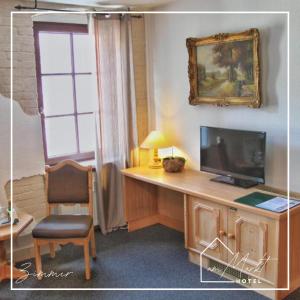 a room with a desk with a television and a chair at Hotel am Markt in Bad Lobenstein