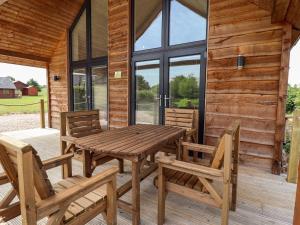 a wooden table and chairs on the porch of a cabin at The Lilac Owl in Lincoln