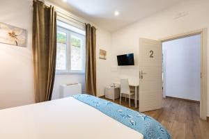 a bedroom with a bed and a desk and a window at Aroma Rooms Procida in Procida