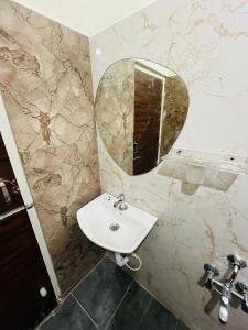 a bathroom with a sink and a mirror at Kalpavrukksha Luxury Service Apartment- Unit 4 - 1 BHK 2 King Size Cot Setup in Chikmagalūr
