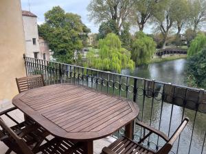 a wooden table and chairs on a balcony with a river at Little Venice in Sacile