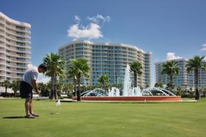 Un uomo sta giocando a golf davanti a una fontana di Caribe Resort Unit C101 a Orange Beach