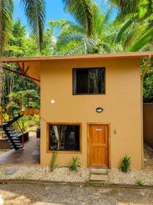 a small yellow house with a wooden door at Corcovado Private Houses-Villas-Tents-Nature-Relaxing in Puerto Jiménez