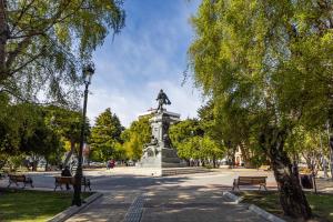 a statue in a park with benches and trees at HOTEL LOS NAVEGANTES in Punta Arenas