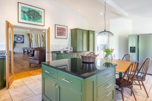 a kitchen with green cabinets and a dining room at Wolmers Barn in Stonham Aspall