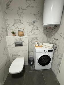 a bathroom with a toilet and a washing machine at City nest Skopje in Skopje